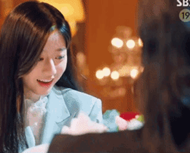 a woman in a suit is sitting at a table with a box of flowers .