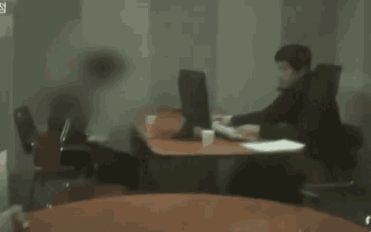 a blurry picture of a man sitting at a desk with a computer .