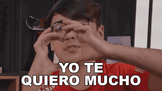 a man wearing glasses and a red shirt says yo te quiero mucho in white letters