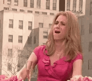 a woman in a pink dress is holding a glass of champagne and crying .