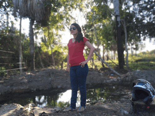 a woman in a red shirt is standing in front of a body of water