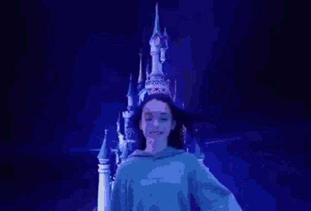 a woman in a crown is standing in front of a fireworks display .