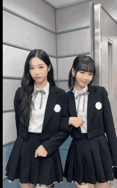 two girls wearing school uniforms pose for a picture