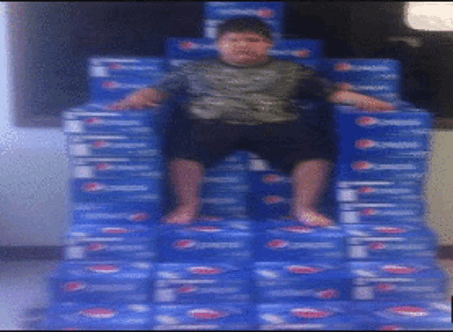 a boy sits on a stack of pepsi boxes