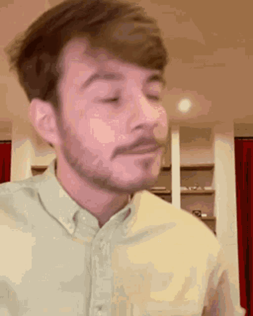 a man with a beard and mustache is wearing a green shirt and making a funny face .