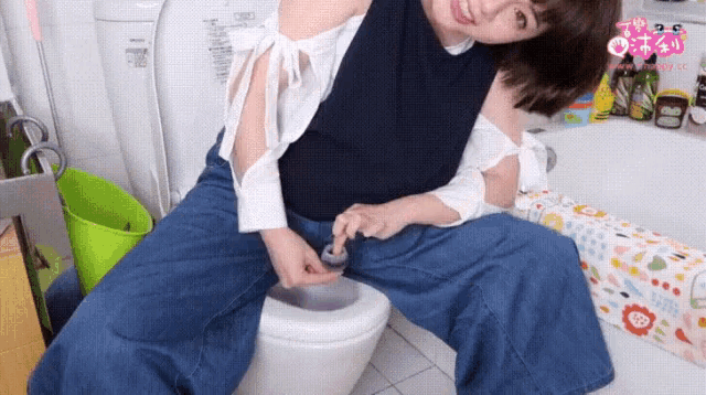 a woman is sitting on a toilet with her legs crossed and holding something in her hand .