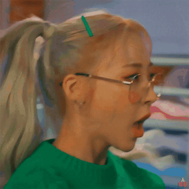 a girl in a green shirt covering her face with her hands