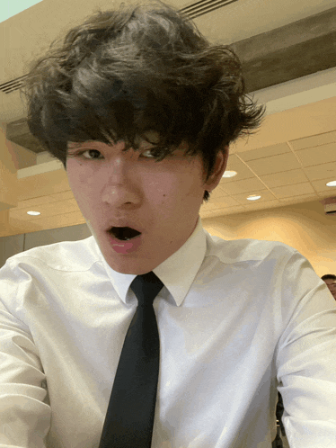 a man wearing a white shirt and black tie looks surprised