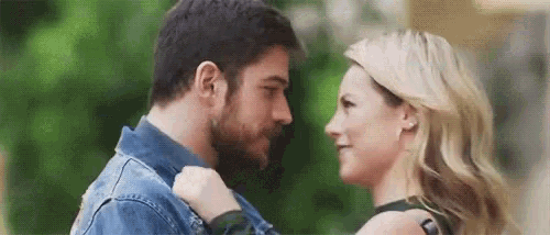 a man and a woman are looking into each other 's eyes while standing next to each other .