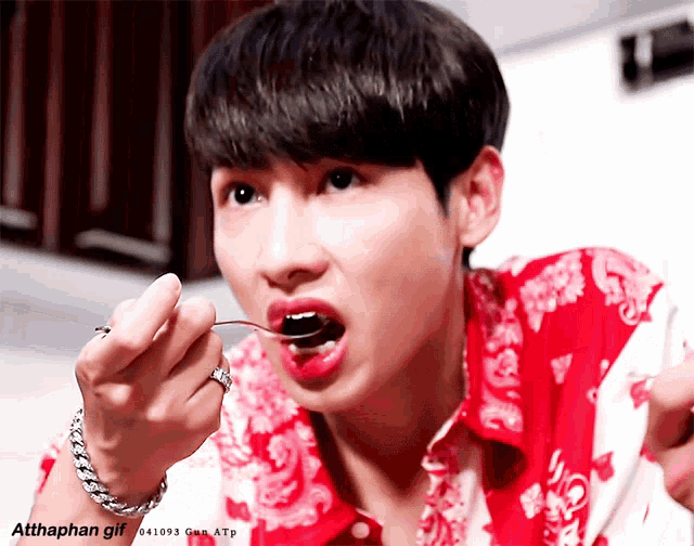 a man in a red and white shirt is eating something