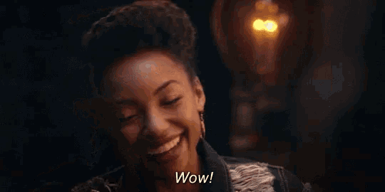 a woman in a denim jacket is making a surprised face and saying wow .