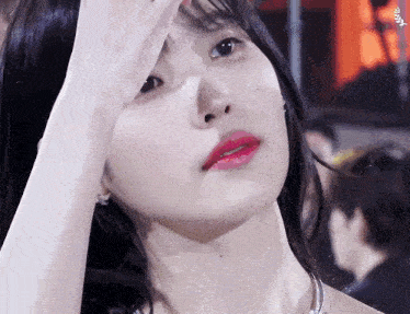 a close up of a woman covering her face with her hand and looking at the camera .