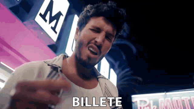 a man with a beard is standing in front of a sign that says " billete "
