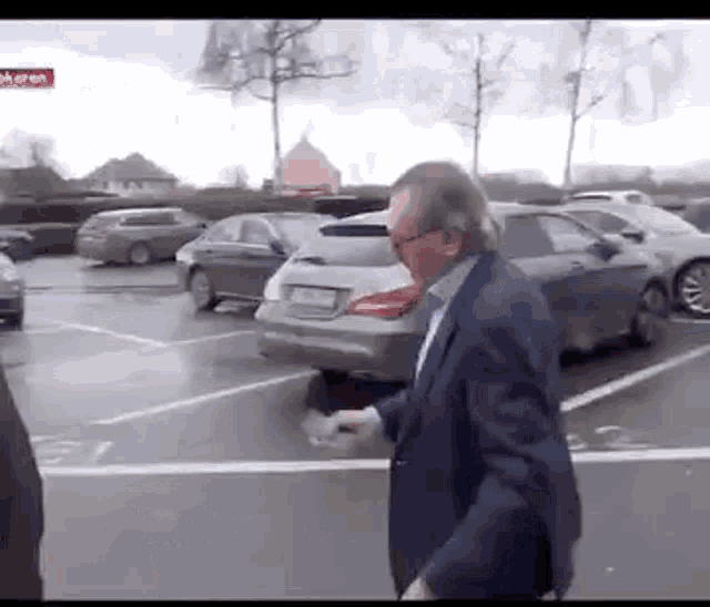 a man in a suit and tie is walking in a parking lot .