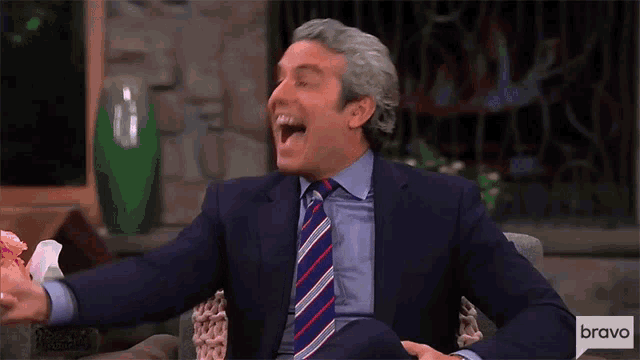 a man in a suit and tie is laughing in front of a sign that says bravo on it