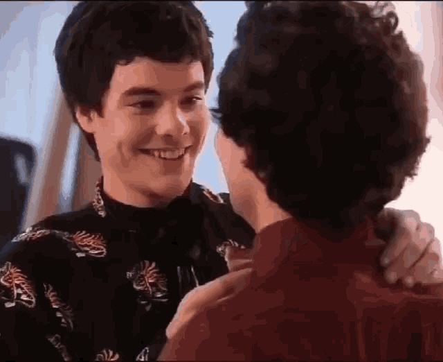 two young men are hugging and smiling at each other .
