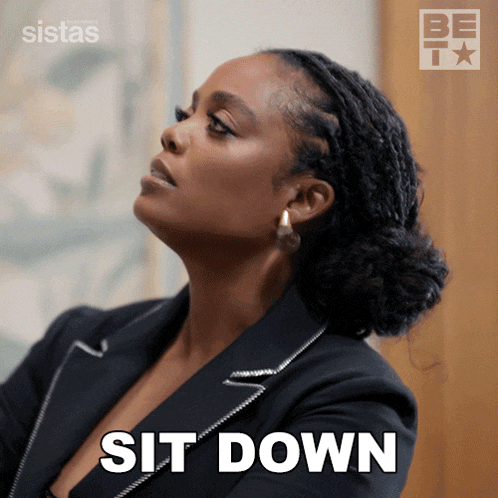 a woman in a suit says sit down in front of a be tv logo
