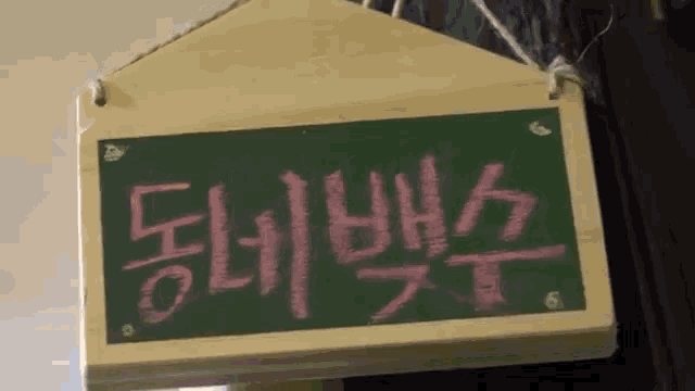 a chalkboard with chinese writing on it is hanging on a wall
