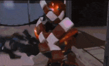 a red and white robot is standing in a room