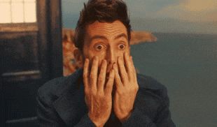 a man covering his face with his hands with a surprised look on his face .