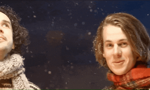 a young man wearing a scarf and mittens waves his hand in the air