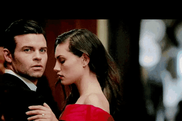 a man in a suit and a woman in a red dress are standing next to each other .
