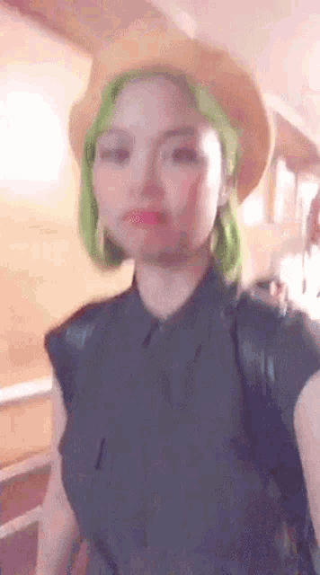 a woman with green hair and a cowboy hat is standing in a room .