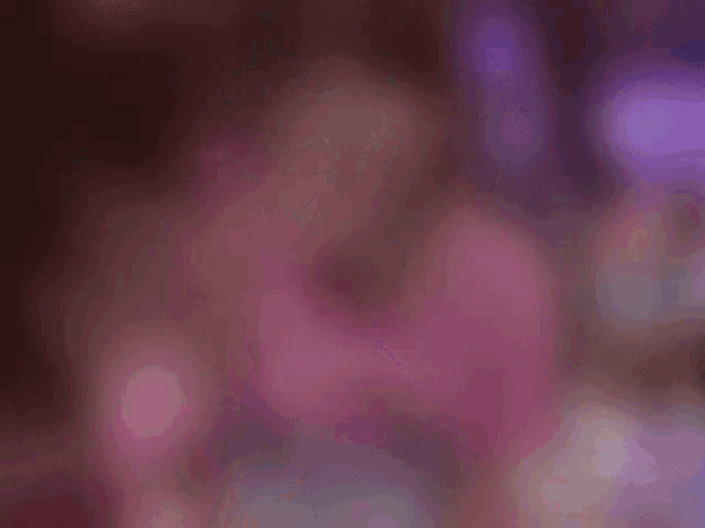 a blurry picture of a woman in a pink shirt holding a purple object .