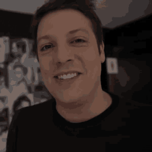 a man in a black shirt smiles and winks