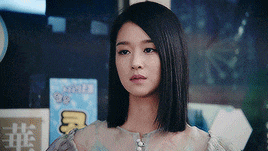 a woman with short hair is standing in front of a sign that says ' chinese ' on it