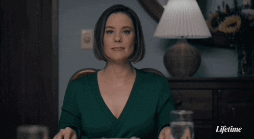 a woman is sitting at a table with a glass of water in front of her and the word lifetime on the bottom