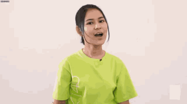 a young woman in a green shirt is smiling and looking at the camera .