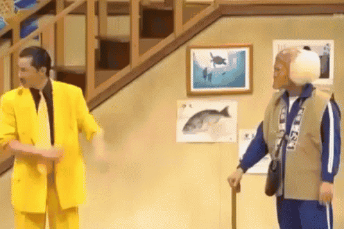 a man in a yellow suit is standing next to a man in a blue jacket holding a cane .
