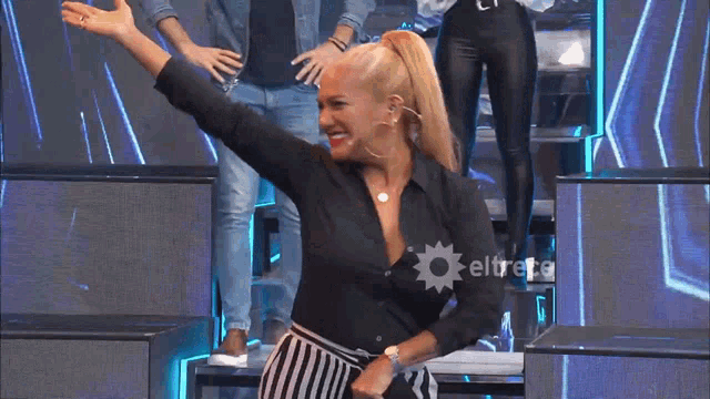 a woman in a black shirt and striped skirt is dancing in front of a eltrece logo