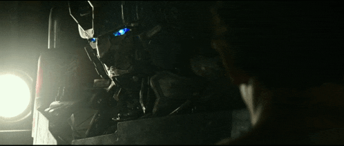 a man is looking at a robot in a dark room with a light shining on it .