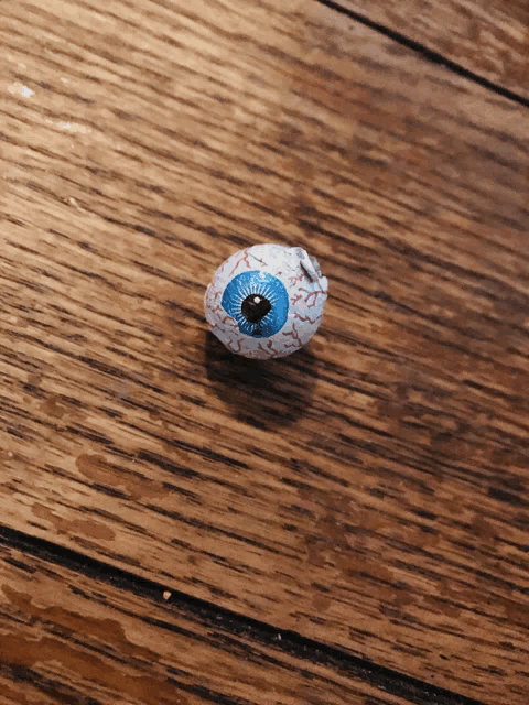 a fake eye with a blue pupil is on a wooden surface