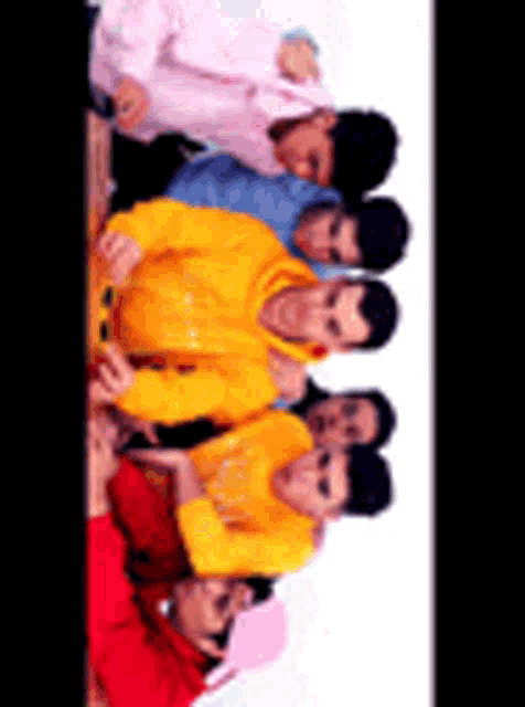 a group of young men are posing for a picture together and one of them is wearing a yellow hoodie .