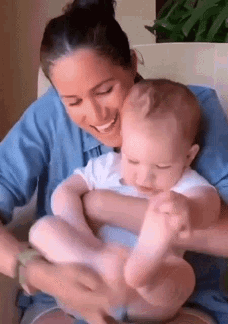 a woman is holding a baby in her arms and smiling at it .