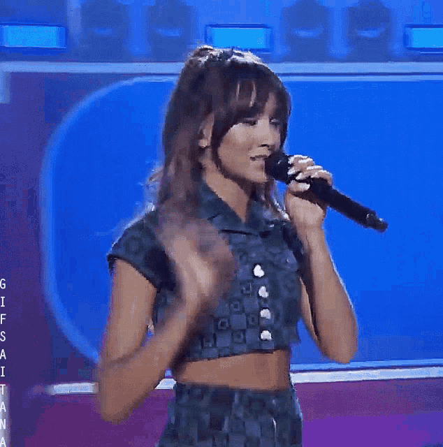 a woman singing into a microphone with the letters g i f s t a n a on the bottom