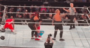 a referee is standing in the middle of a wrestling ring with wrestlers