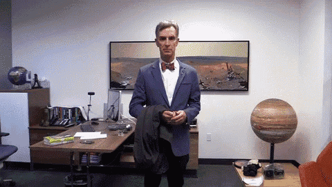 a man in a suit and bow tie stands in an office