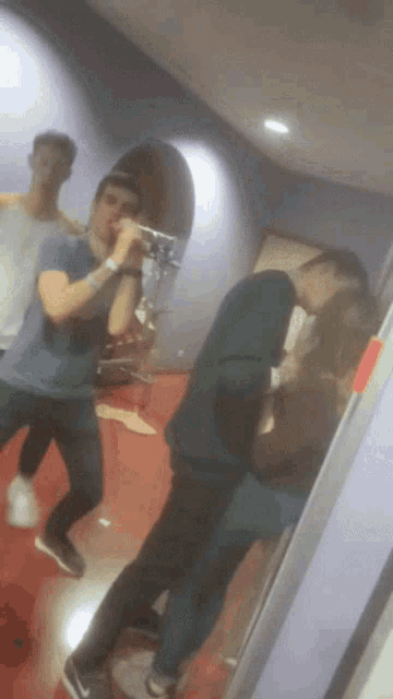 a group of people are dancing in a room and one of them is taking a picture of himself