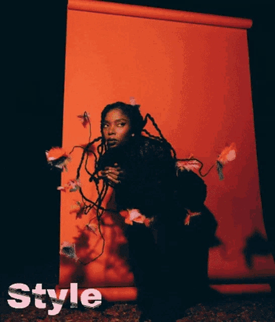 a woman with dreadlocks is sitting in front of a red background with the word style written on it