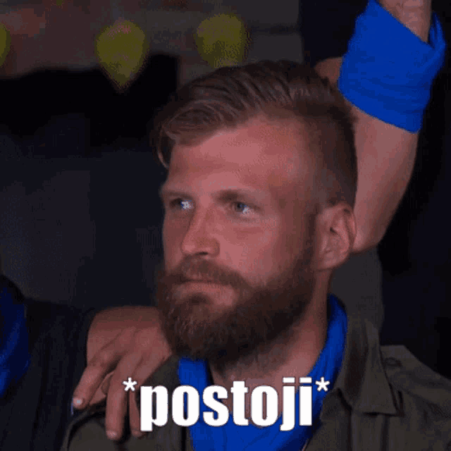 a man with a beard and a blue scarf around his neck has the word postoji written on his face