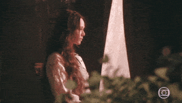 a woman looks out from behind a curtain with the letters o on it