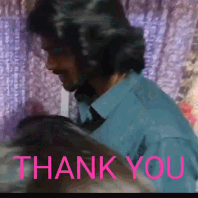 a man in a blue shirt is standing in front of a thank you sign