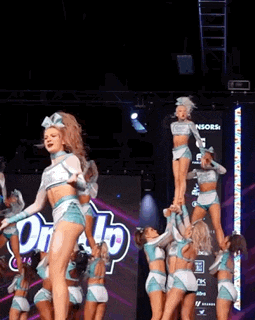 a group of cheerleaders are performing on a stage in front of a sign that says sponsors