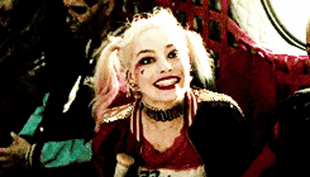 a woman in a harley quinn costume is smiling and looking at the camera
