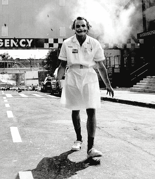 a man in a nurse 's uniform is walking down a street in front of an emergency room