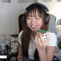 a woman wearing headphones is holding a green cube in her hand and smiling .